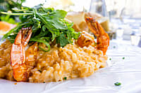 Tasty risotto with Shrimp, fresh herbs vegetables on a white plate