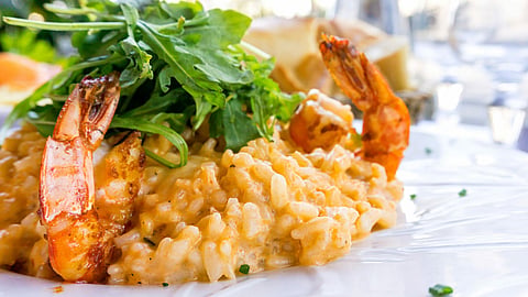Tasty risotto with Shrimp, fresh herbs vegetables on a white plate